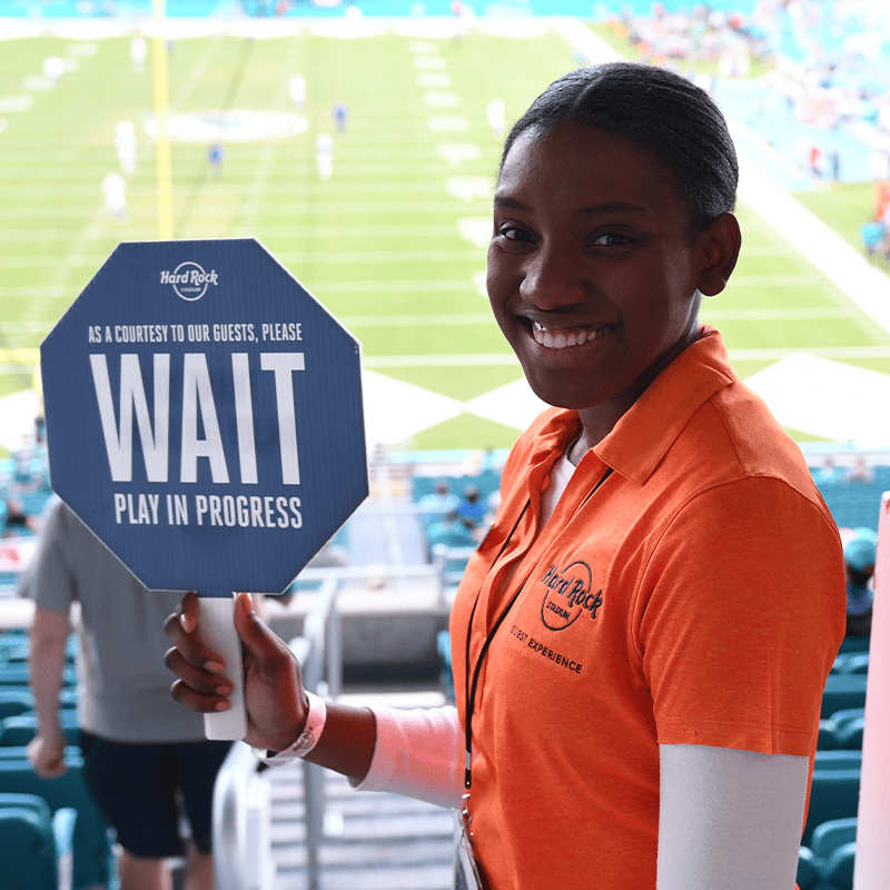 A Guest Experience Employee Holds up a sign at Hard Rock Stadium